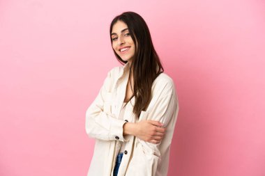 Pembe arka planda izole edilmiş genç beyaz kadın gülüyor.