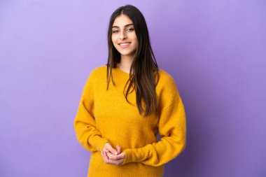 Mor arka planda izole edilmiş genç beyaz kadın gülüyor.