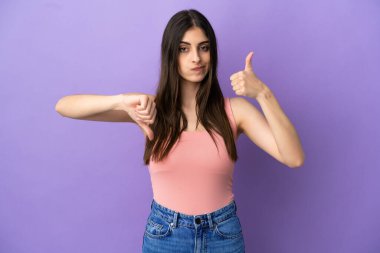 Mor arka planda izole edilmiş beyaz bir kadın iyiye-kötüye işaret yapıyor. Evet ya da hayır arasında kararsız