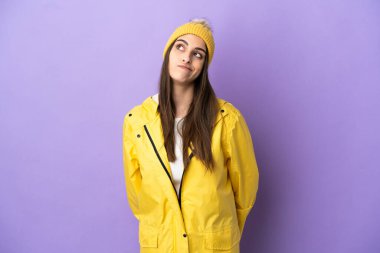 Mor arka planda izole edilmiş, yağmura dayanıklı bir ceket giyen beyaz bir kadın.