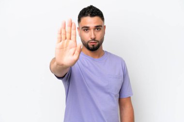 Beyaz arka planda izole edilmiş genç Arap yakışıklı adam dur hareketi yapıyor.