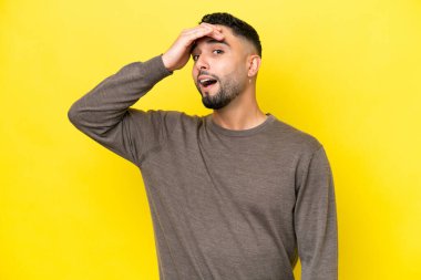 Sarı arka planda izole edilmiş genç, yakışıklı Arap bir adam. Yan tarafa bakarken sürpriz jest yapıyor.