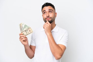Genç bir Arap, beyaz arka planda izole edilmiş bir sürü para alıyor.