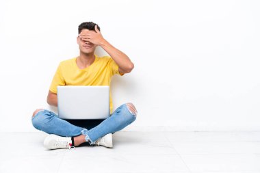 Yerde oturan genç adam, beyaz arka planda tek başına, gözleri elleriyle kapatıyor. Bir şey görmek istemiyorum.