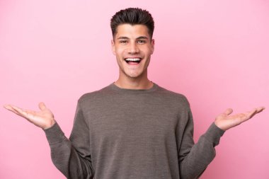 Pembe arka planda yüzü şoke olmuş genç beyaz bir adam.