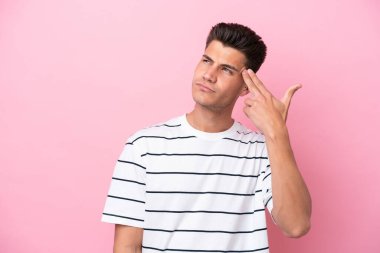 Genç beyaz adam pembe arka planda izole edilmiş ve intihar jesti yapmada sorun yaşıyor.