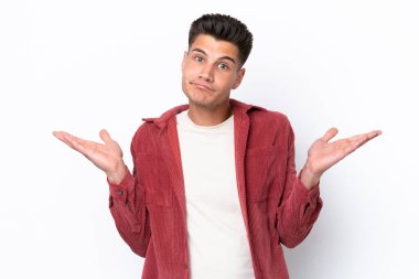 Beyaz arka planda izole olmuş genç beyaz bir adam şüphe içinde el kaldırırken