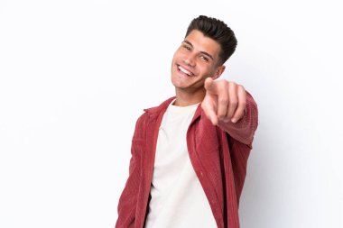 Beyaz arka planda izole edilmiş genç beyaz adam mutlu bir ifadeyle ön tarafı işaret ediyor.