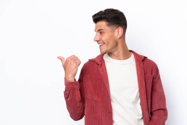 Beyaz arka planda izole edilmiş genç beyaz bir adam bir ürün sunmak için kenarı işaret ediyor.