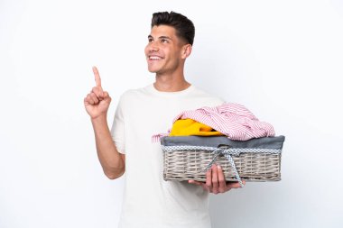 Young caucasian man holding laundry basket isolated on white background pointing up a great idea