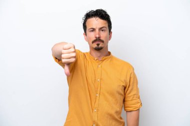 Bıyıklı genç adam beyaz arka planda izole edilmiş, başparmağını negatif ifade ile aşağı gösteriyor.