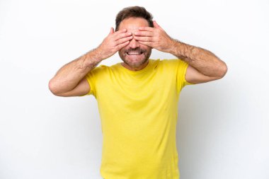 Beyaz arka planda izole edilmiş orta yaşlı beyaz bir adam gözlerini elleriyle kapatıyor ve gülümsüyor.