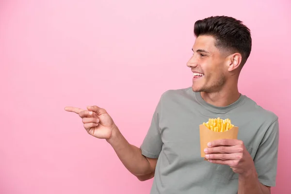 Jonge Blanke Man Met Gebakken Chips Geïsoleerd Roze Achtergrond Wijzende — Stockfoto