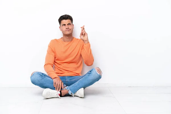 Young Man Sitting Floor Isolated White Background Fingers Crossing Wishing — Stok fotoğraf