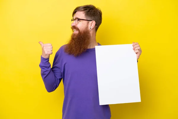 红头发男子 胡须孤立在黄色的背景上 手持一个空的标语牌 指向一边 — 图库照片