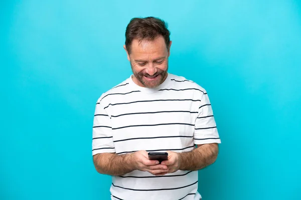 青い背景に隔離された中世の白人男性携帯電話でメッセージを送る — ストック写真