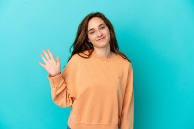 Mavi arka planda izole edilmiş beyaz bir kadın. Mutlu bir ifadeyle selamlıyor.