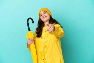 Mavi arka planda şemsiyesi olan beyaz bir adam mutlu bir ifadeyle öne bakıyor.