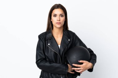 Beyaz arka planda motosiklet kaskı tutan beyaz kız kollarını kavuşturuyor.