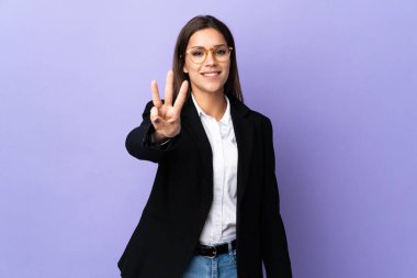 Mor arka planda izole edilmiş iş kadını mutlu ve parmaklarıyla üçe kadar sayıyor.