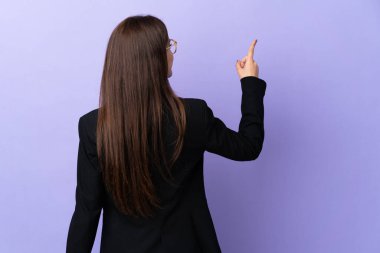 Mor arka planda izole edilmiş bir iş kadını işaret parmağıyla işaret ediyor