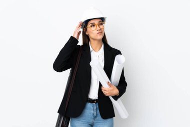 Miğferli, kafkas kafalı genç bir kadın izole edilmiş arka plan üzerinde planları tutuyor. Şüpheleri var ve kafası karışmış bir yüz ifadesi var.