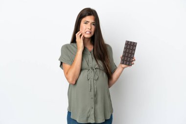 Genç Brezilyalı bir kadın beyaz arka planda izole edilmiş hamile ve elinde aç çikolatayla