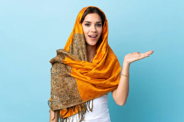 ヤシの上に架空のコピースペースを保持青い背景に隔離された伝統的な衣装を持つ若いモロッコの女性は 広告を挿入します — ストック写真