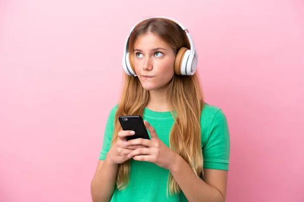 Νεαρή Ξανθιά Γυναίκα Απομονωμένη Ροζ Φόντο Ακούγοντας Μουσική Κινητό Και — Φωτογραφία Αρχείου