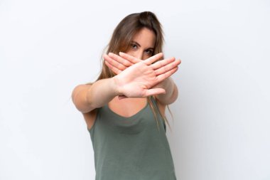 Beyaz arka planda izole edilmiş genç beyaz bir kadın bir eylemi durdurmak için el hareketi yapıyor.