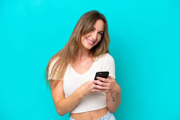 Mavi Arka Planda Izole Edilmiş Genç Beyaz Kadın Cep Telefonuyla — Stok fotoğraf