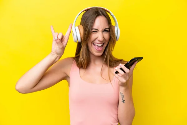 Joven Mujer Caucásica Aislada Sobre Fondo Amarillo Escuchando Música Con —  Fotos de Stock