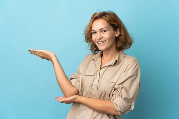 Jonge Georgische Vrouw Geïsoleerd Blauwe Achtergrond Reiken Handen Naar Zijkant — Stockfoto