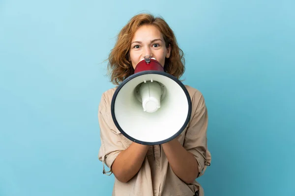 stock image Young Georgian woman isolated on blue background shouting through a megaphone