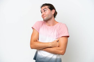 Beyaz arka planda beyaz tenli yakışıklı bir adam omuzlarını kaldırırken şüpheyle hareket ediyor.