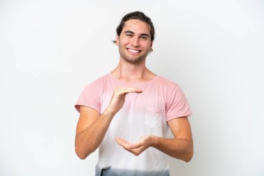 Beyaz arka planda izole edilmiş beyaz tenli yakışıklı bir adam, bir ilan vermek için avucunun içinde hayali bir mekan tutuyor.