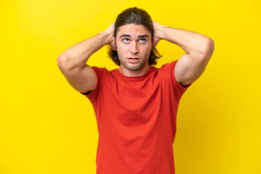 Caucasian handsome man isolated on yellow background frustrated and covering ears