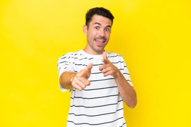 Izole sarı arka plan üzerinde genç yakışıklı adam şaşırttı ve ön işaret