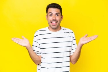 Yüzünde şok ifadesi olan, izole edilmiş sarı arka planda genç yakışıklı bir adam.