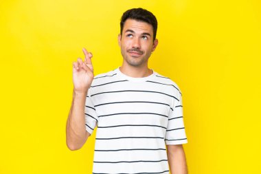 Genç yakışıklı, izole edilmiş sarı arka planda, şans diliyor ve en iyisini diliyor.