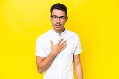 Soyutlanmış sarı arka planı olan yakışıklı genç bir adam kendini işaret ediyor.