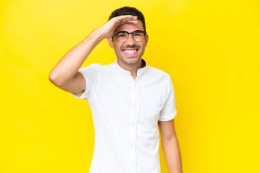 Soyutlanmış sarı arka planda genç yakışıklı bir adam uzaklarda bir şeye bakıyor.