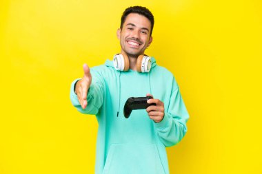 Genç yakışıklı bir adam, izole bir duvarın üzerinde bilgisayar oyunu kontrolörüyle oynuyor ve iyi bir anlaşma için el sıkışıyor.