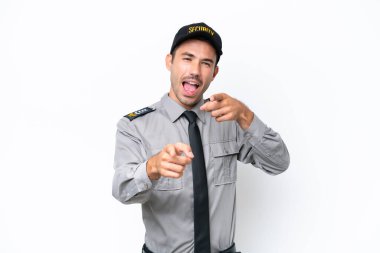 İzole edilmiş beyaz arka planda genç bir koruma ön tarafı işaret ediyor ve gülümsüyor.