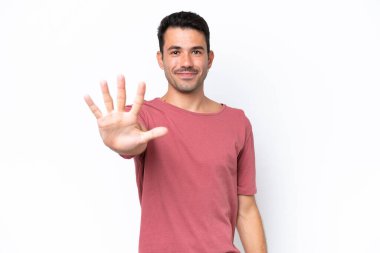 Soyutlanmış beyaz arka planda genç yakışıklı adam parmaklarıyla beşi sayıyor.