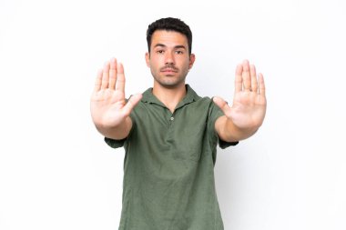 Soyutlanmış beyaz arka planda genç yakışıklı adam dur hareketi yapıyor ve hayal kırıklığına uğruyor.