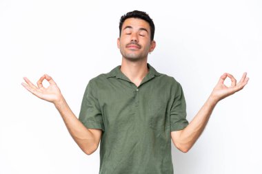 Zen pozisyonunda soyutlanmış beyaz bir geçmişi olan yakışıklı bir genç.