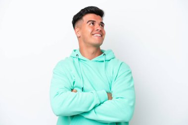 Beyaz arka planda soyutlanmış beyaz tenli yakışıklı adam gülümserken yukarı bakıyor.