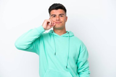 Beyaz arka planda izole edilmiş beyaz tenli yakışıklı genç bir adam sessizlik işareti gösteriyor.