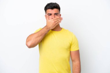 Beyaz arka planda izole edilmiş beyaz tenli yakışıklı bir adam. Ağzını eliyle kapatıyor.